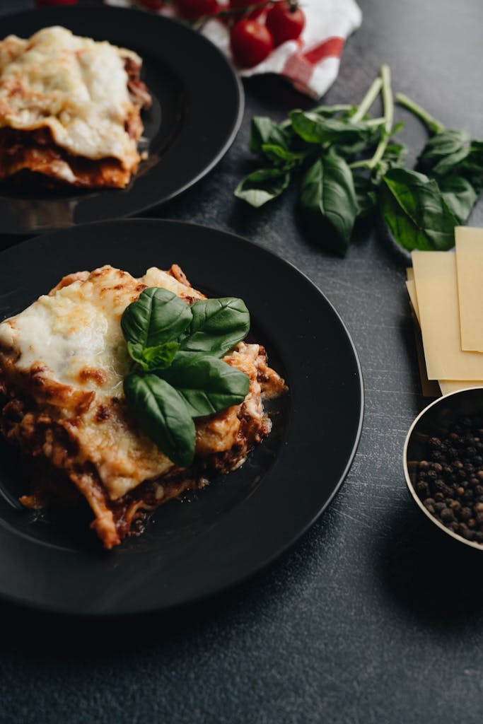 Lasagna on Black Plate With Basil Leaves On Top